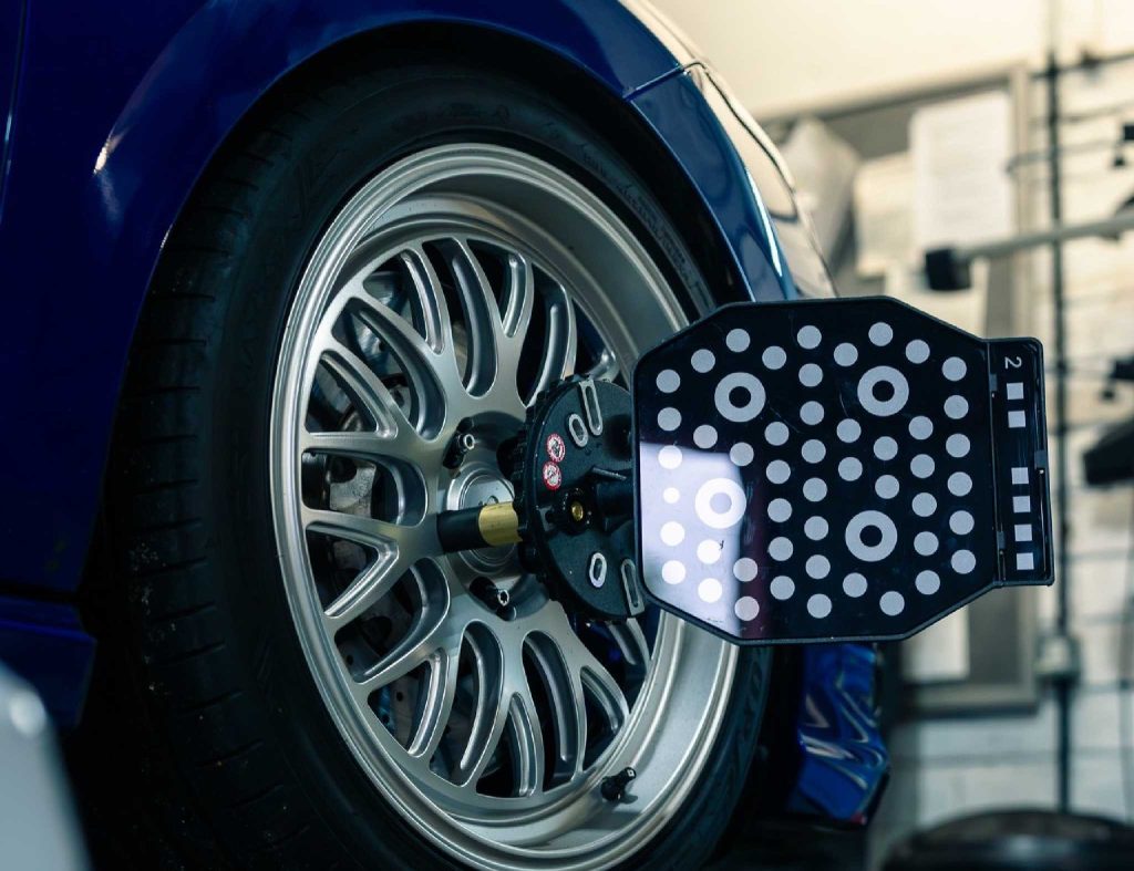 tył samochodu z kołami rozstawionymi na zewnątrz podczas pomiaru w warsztacie