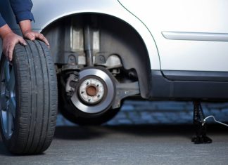 Zbieżność kół, pochylenie, kąt wyprzedzenia – trzy ustawienia geometrii, które decydują , czy samochód jedzie prosto samochód na podnośniku z mechanikiem mierzącym kąty kół laserowym przyrządem